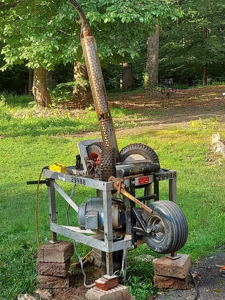 Portable pump hoist pulling a submersible well pump up out of the casing on a Maryland lawn